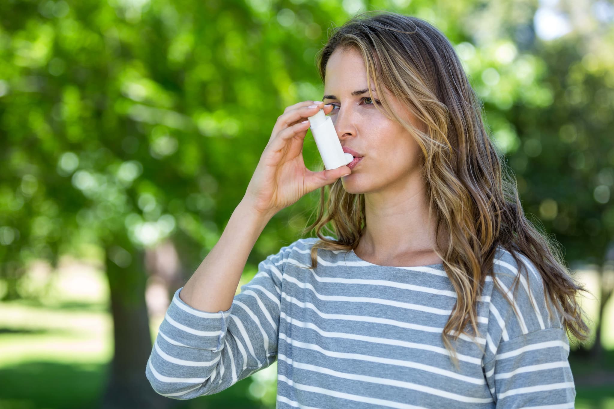 Woman using inhaler for asthma treatment